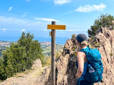 Wanderin mit Wegweiser am Coll de la Serra