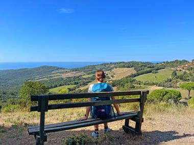 Hiker sitting on a bench with a hilly landscape in the background