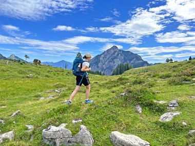 Wandern in der Postalm Region Wanderin inmitten einer Almlandschaft, Berge im Hintergrund, grüne Wiesen