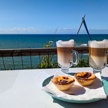 Kaffee und Pastel de Nata mit Meeresblick