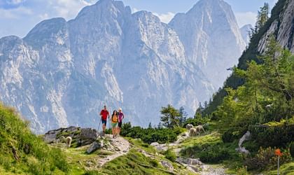 Three hikers on the Vrsic Pass with an imposing mountain backdrop