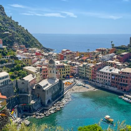 Vernazza village in Cinque Terre with colorful houses on a rocky peninsula, turquoise harbor, and historic tower overlooking the Mediterranean Sea.