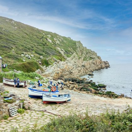 Fischerboote und ein landestypischen Steinhaus an der felsigen Küste von Cornwall