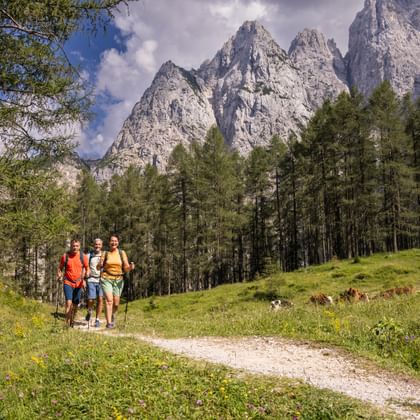 Three hikers on the Vrsic Pass with a view of the mountains