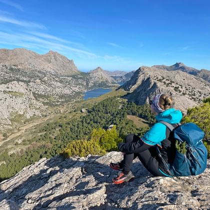 Hiker at the Coll de l'Ofre pass with a view of the Cuber reservoir