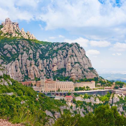 Panoramasicht auf das Kloster Montserrat mit felsigen Bergen und weiter Ebene im Hintergrund
