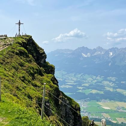 Blick auf den Wanderweg zum Gipfelkreuz, mit dem Tal und dem Wilden Kaiser im Hintergrund