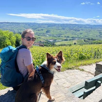 Wanderer und Hund mit Blick auf die Weinlandschaft des Piemonts