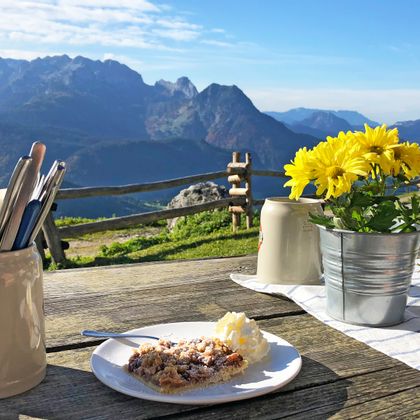 Plum cake at the table on the alpine pasture on the Gosaukamm with mountain panorama