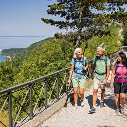 Hikers on the ridgeway near Trieste, with a view of Miramare Castle