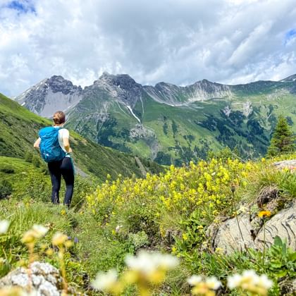 Hiker on the E5 and with a view of the mountain panorama of the Alps