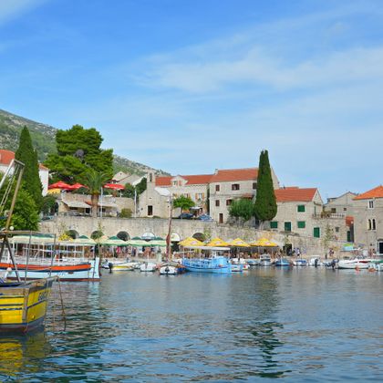 Ein Hafen mit den landestypischen Steinhäusern und bunten Ausflugs- und Fischerbooten auf der Insel Brac