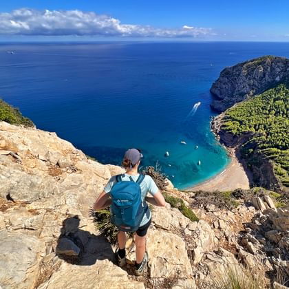 Wanderer blickt auf die türkis-blaue Bucht von Coll de Baix