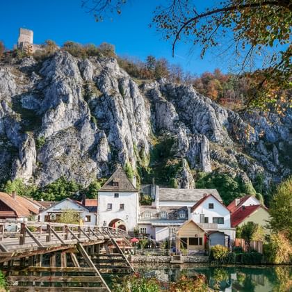 Dramatic white limestone cliffs rising above a village along the Main-Danube Canal in Altmühltal. Houses with red roofs nestle at the cliff base.