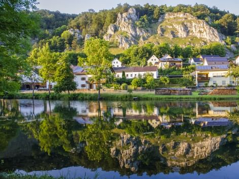 Bayerisches Dorf mit weißen Häusern am Main-Donau-Kanal im Altmühltal, vor dramatischen Kalksteinfelsen und Wäldern.