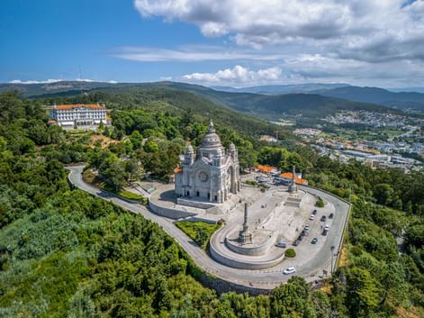 Aerial view of Basilica da Santa Luzia in Viana do Castelo, surrounded by green hills and overlooking the city and mountains.