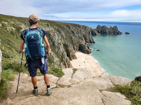 Wanderin genießt von einer Klippe den Blick auf den Pedn Vounder Beach