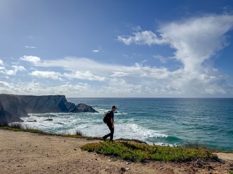 Wanderer mit Rucksack auf Küstenklippe mit Blick auf den Atlantik am portugiesischen Jakobsweg von Porto nach Santiago de Compostela.