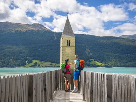 Hikers have a view of the turquoise Lake Resia with its sunken church tower