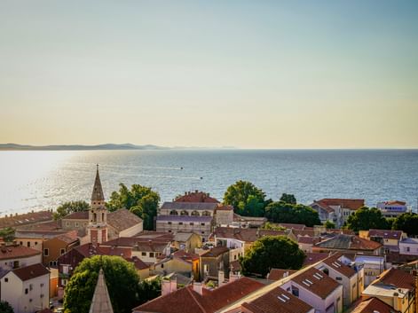 Aerial view of Zadar's old town with red-tiled roofs, a church tower, and the Adriatic Sea in Northern Dalmatia, Croatia.