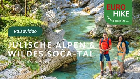 Zwei Wanderer mit Rucksäcken und Stöcken stehen am türkisfarbenen Soča-Fluss in den Julischen Alpen. Flussbett und grüner Wald sichtbar.