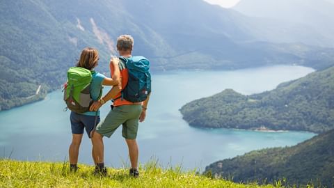 Hikers admire the beautiful Lake Molveno surrounded by mountains