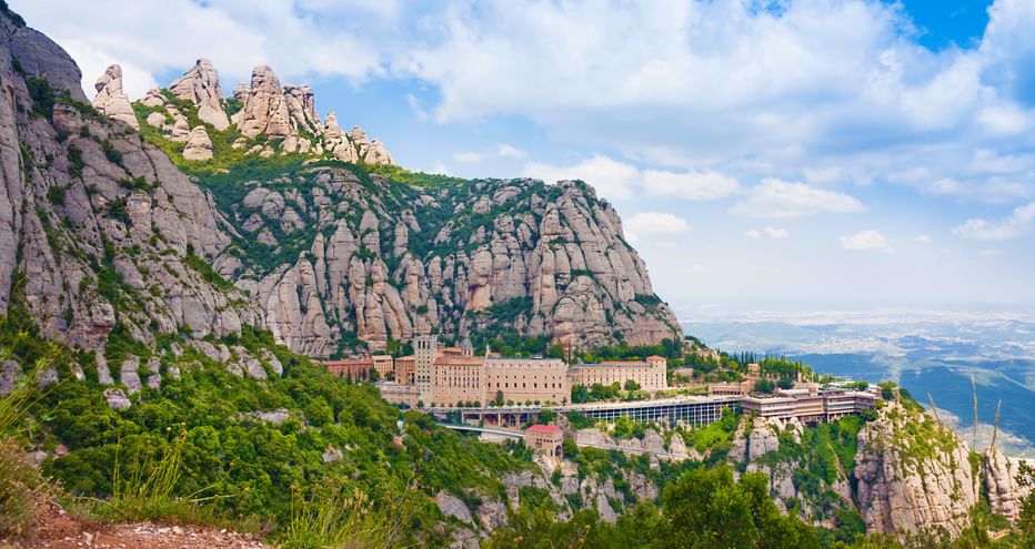 Panoramasicht auf das Kloster Montserrat mit felsigen Bergen und weiter Ebene im Hintergrund