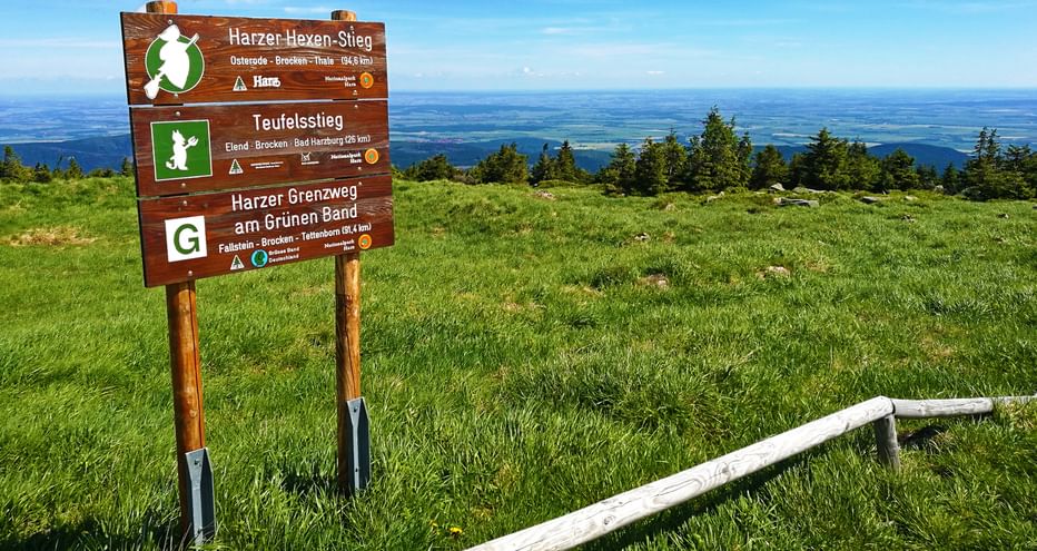 On the Brocken with wooden hiking board and view into the valley