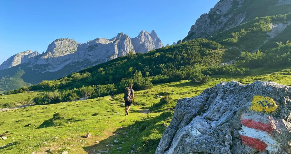 Trail marking on the Gosaukamm with hiker and mountains in the background