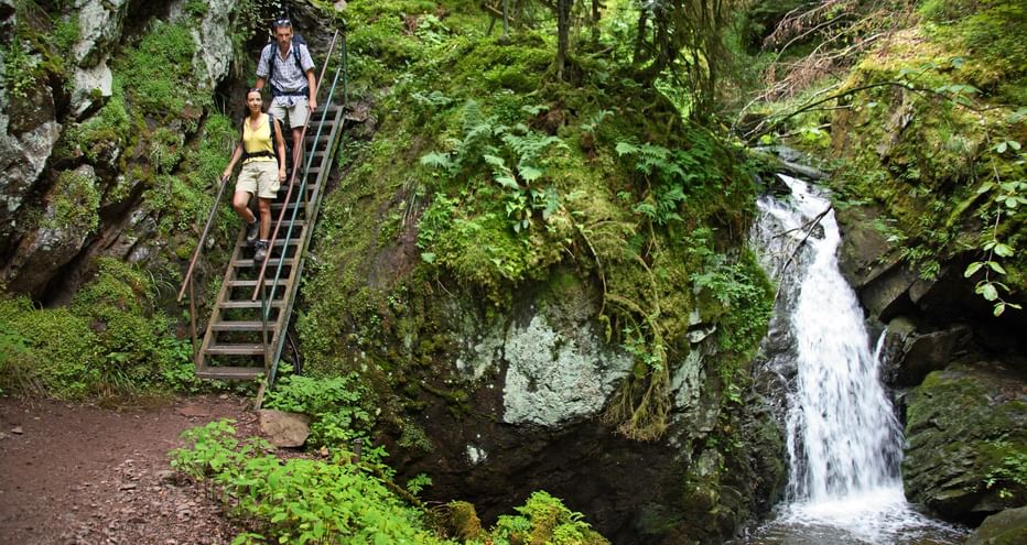 2 Wanderer auf einem Wanderweg neben einem bezaubernden Wasserfall im Schwarzwald