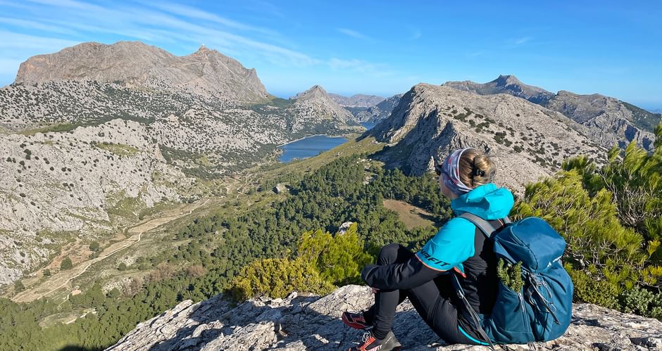 Hiker at the Coll de l'Ofre pass with a view of the Cuber reservoir