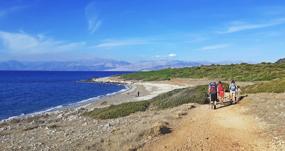 Hikers on the stony coast of Agia Ekaterin, mountain panorama in the background