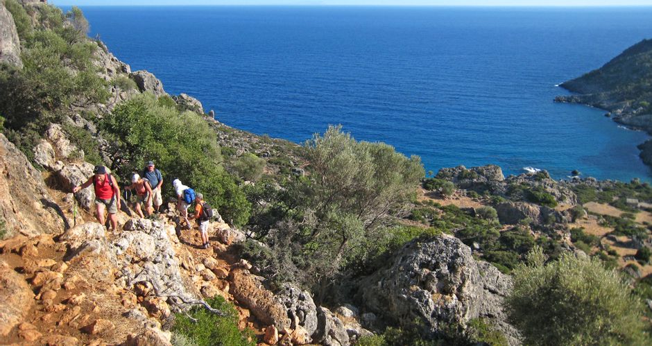 Hikers on the rocky ascent at Lissos, with the coast in the background