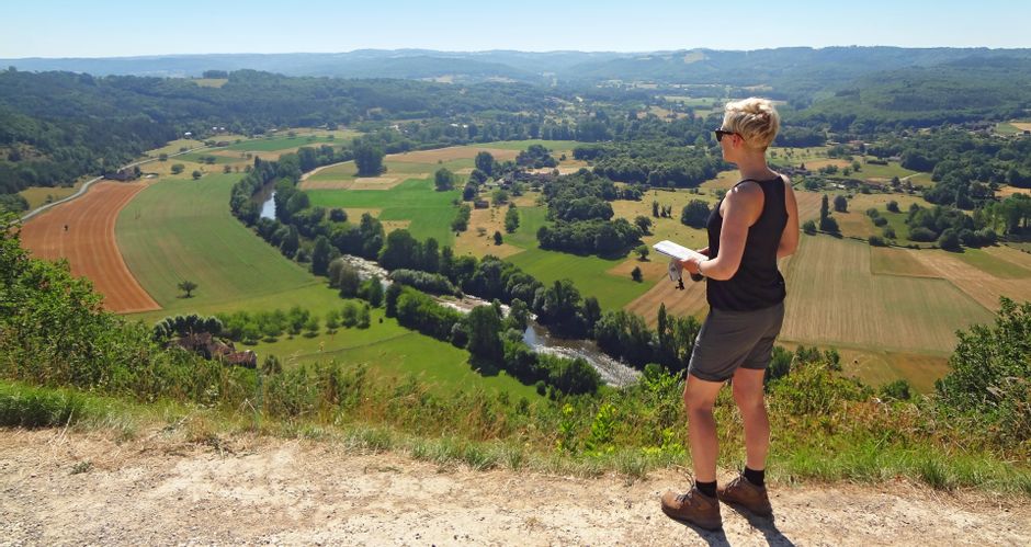 Wanderin mit Tourenkarte mit blick auf das Tal der Dordogne