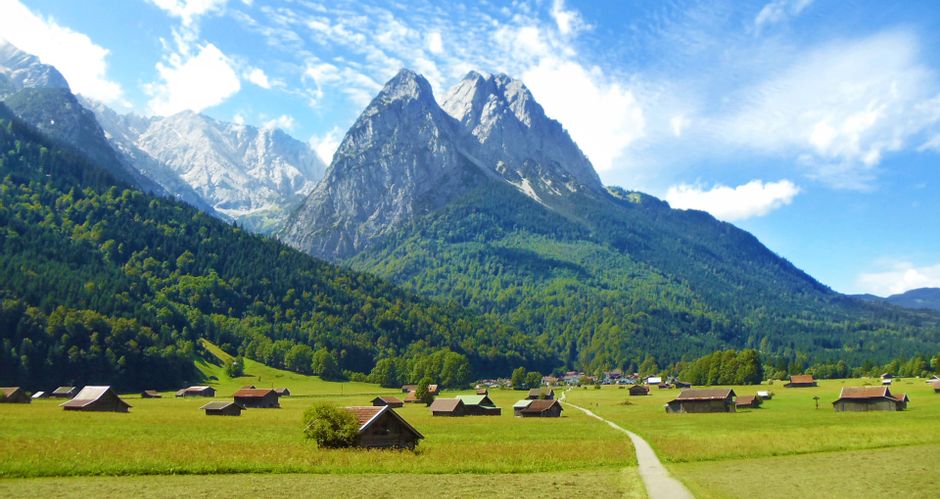 View of the Zugspitze with huts and meadows in the foreground