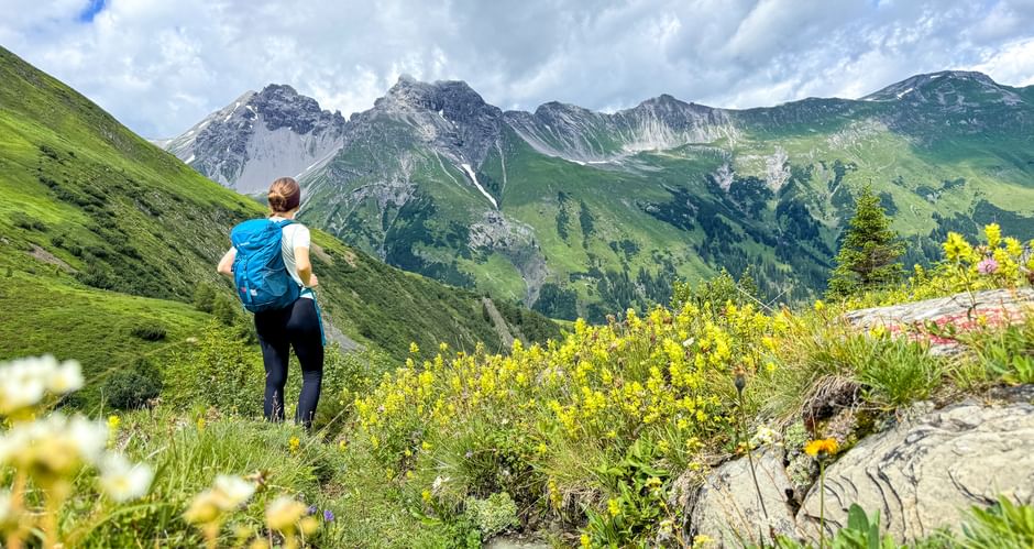 Hiker on the E5 and with a view of the mountain panorama of the Alps