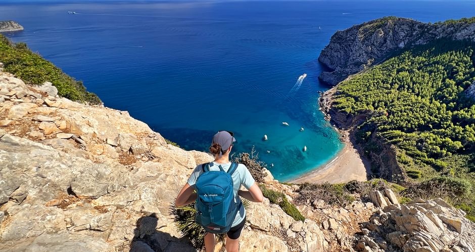 Wanderer blickt auf die türkis-blaue Bucht von Coll de Baix