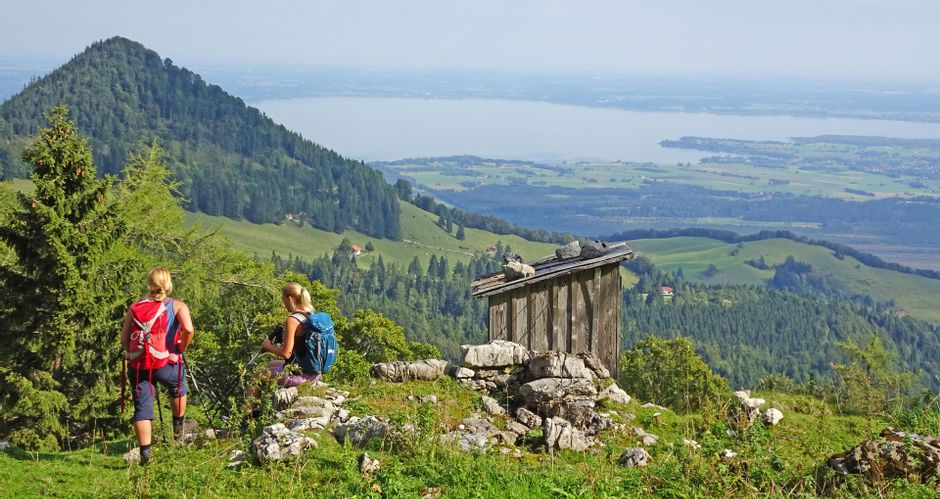 Zwei Wanderinnen auf einer Almwiese mit Blick auf den Friedenrath und denChiemsee