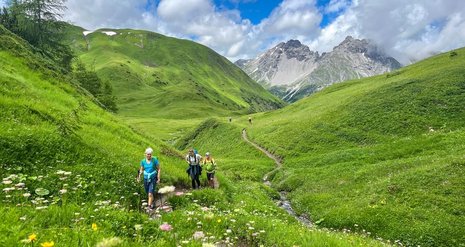 Wanderer auf einer Almwiese von Steeg nach Landeck